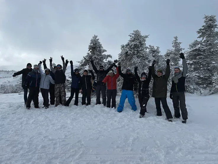 Un groupe de personnes est debout dans la neige, les bras levés en l'air pour la photo.